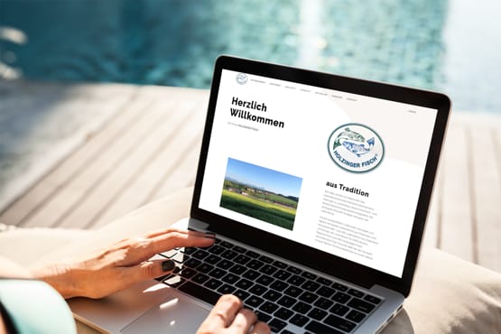 Person benutzt Laptop am Pool, Webseite mit Begrüßungstext und Landschaftsbild auf dem Bildschirm